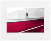 A limited edition museum-quality photograph featuring an abstract urban scene with a predominantly red color, a white geometric pattern, and a small figure in the distance.