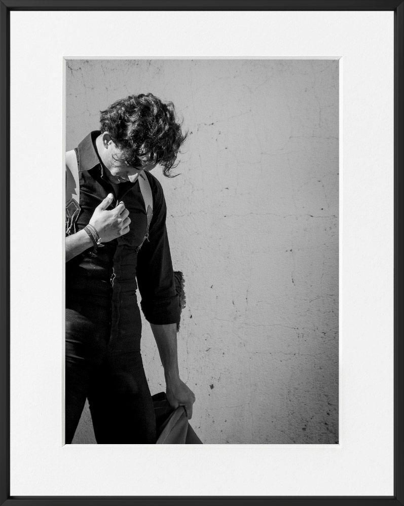 A person with curly hair and a collared shirt is partially visible against a textured, light-colored wall.
