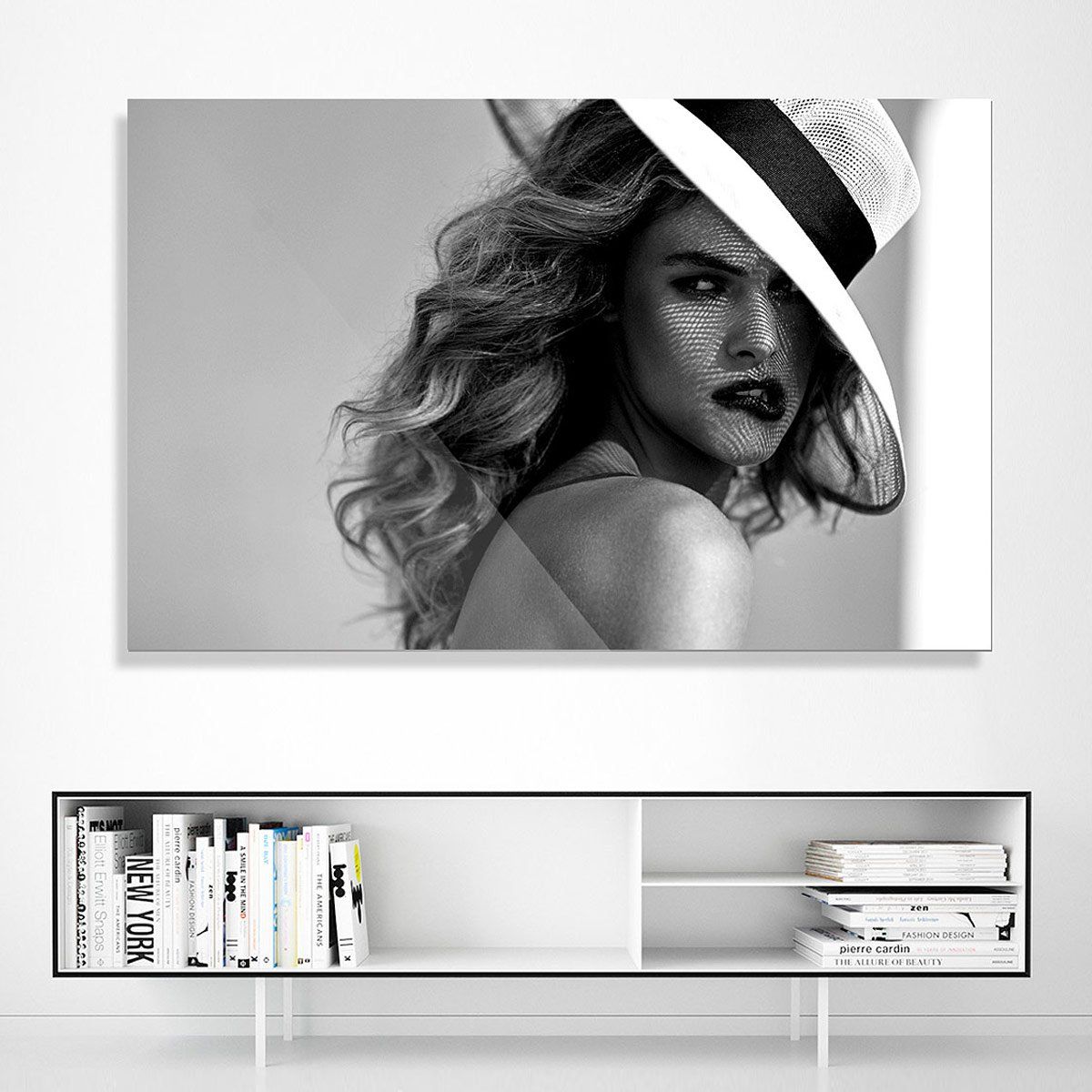 A black-and-white portrait shows a woman with wavy hair wearing a wide-brimmed hat, her face partially in shadow.