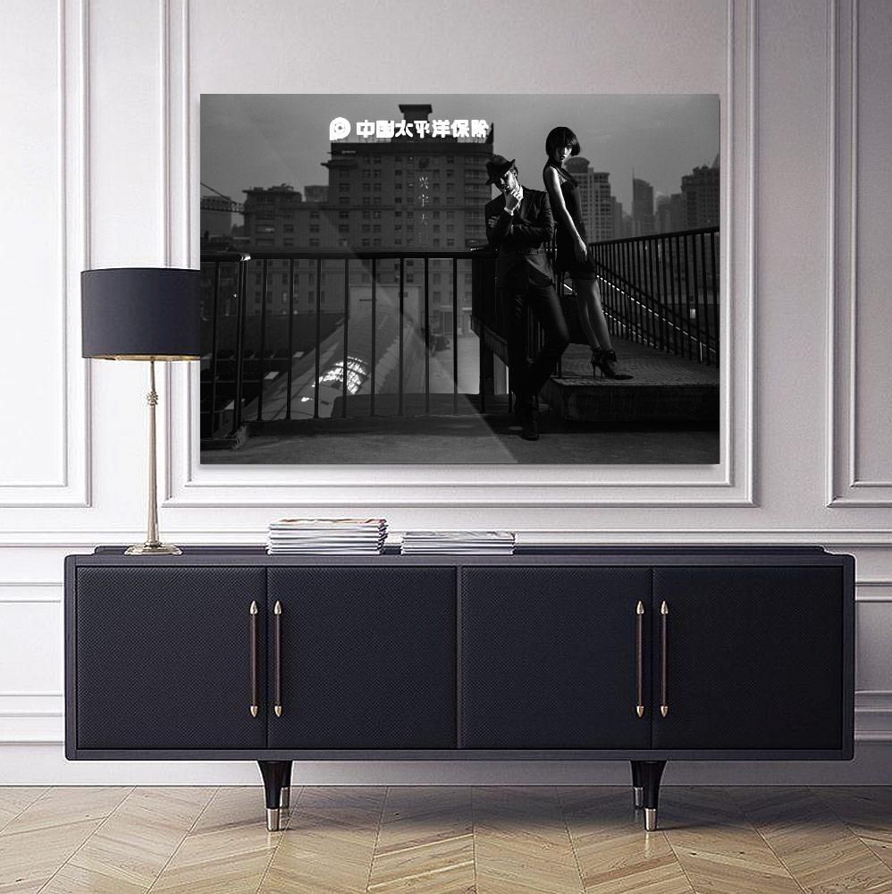 A dark sideboard with brass handles stands against a paneled wall, topped with stacked magazines and a tall lamp with a black shade.