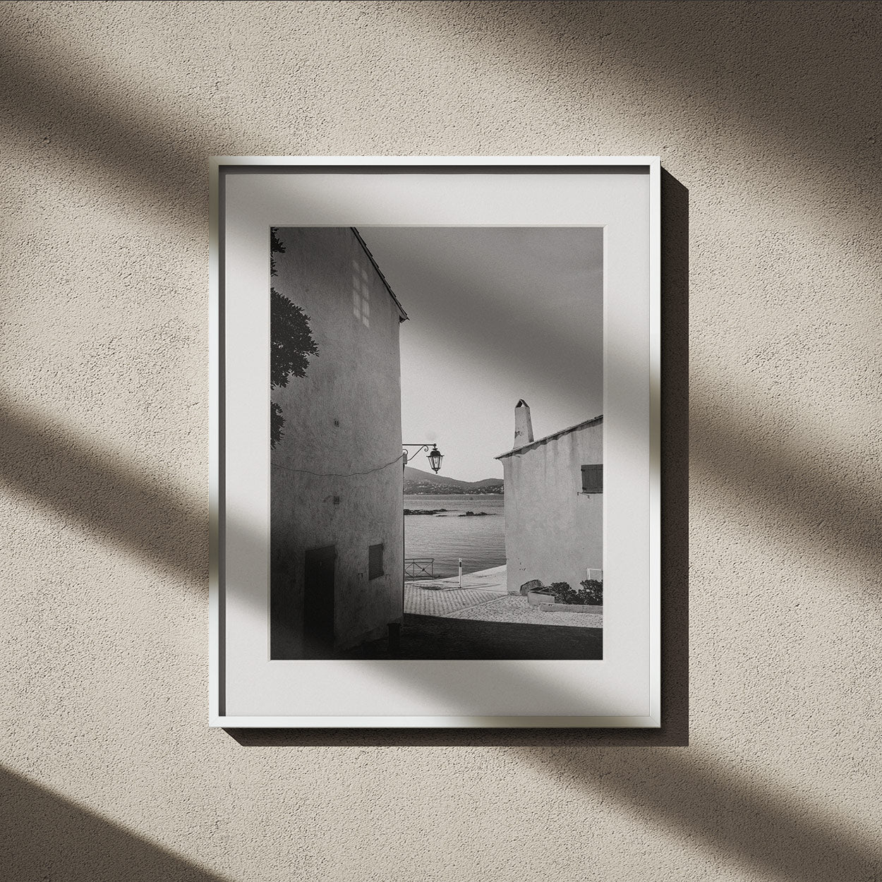 A narrow alleyway with stone walls leads into shadow, with sunlight falling on the textured ground in the foreground.