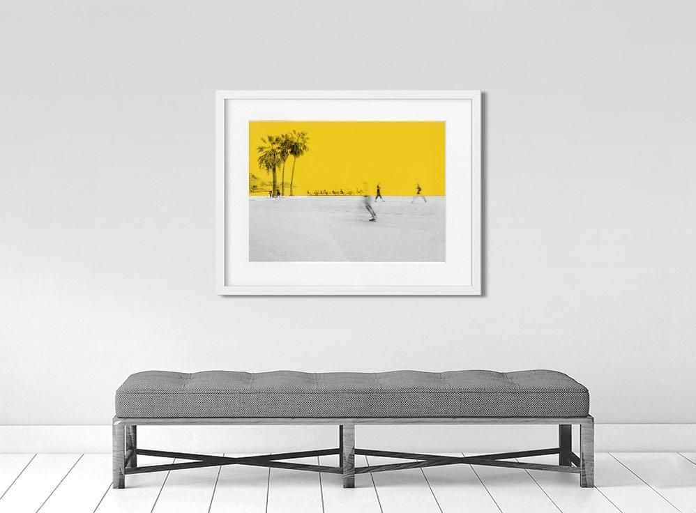 A limited edition museum-quality photograph featuring a vibrant yellow sky with palm trees in the background, and a white foreground with silhouettes of people.
