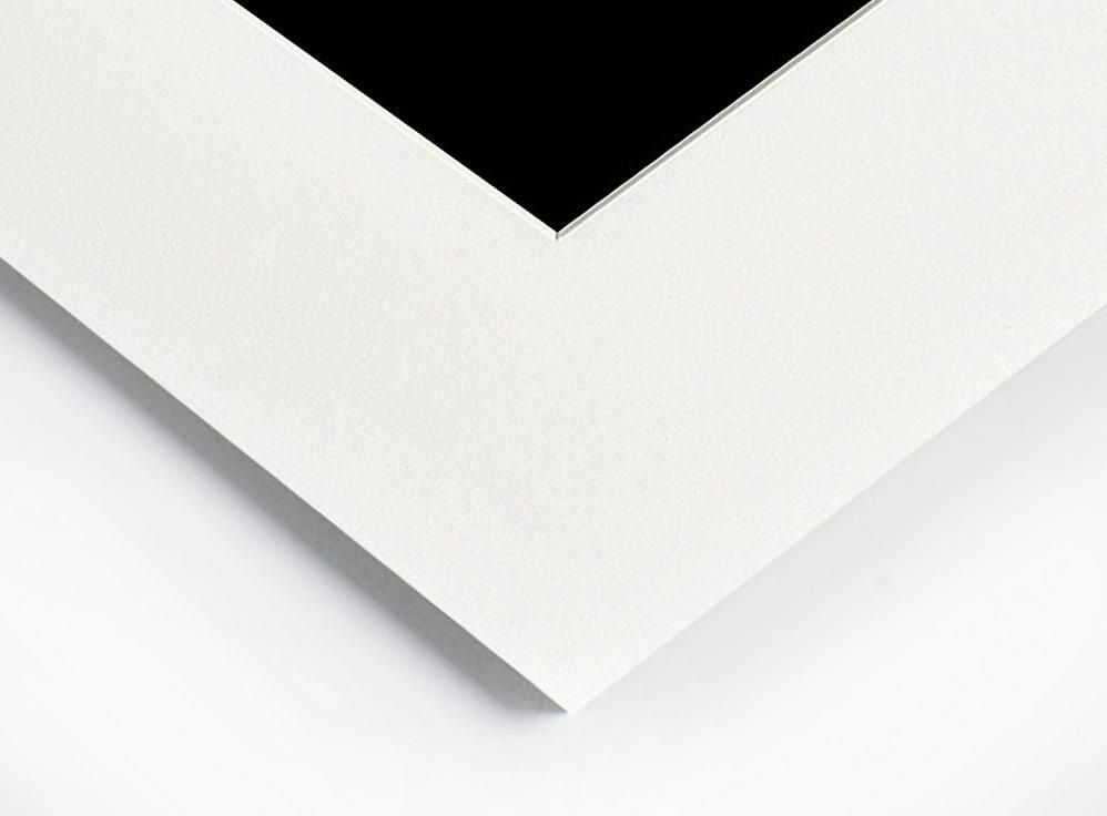 A sharp corner of a white mat board frames a solid black rectangular area against a white background.