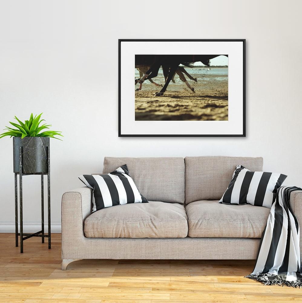 A beige sofa with two black and white striped pillows sits on a light wood floor beside a tall potted plant.