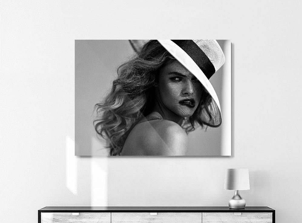 A black-and-white portrait shows a woman with wavy hair wearing a wide-brimmed hat, her face partially covered by netting.